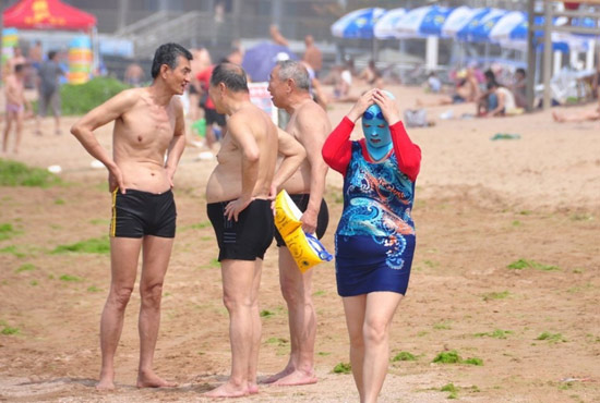 2013年7月3日，山東青島青島高溫來襲，“青島大媽”不懼滸苔，戴著“強盜面具”出現(xiàn)在海水浴場消暑降