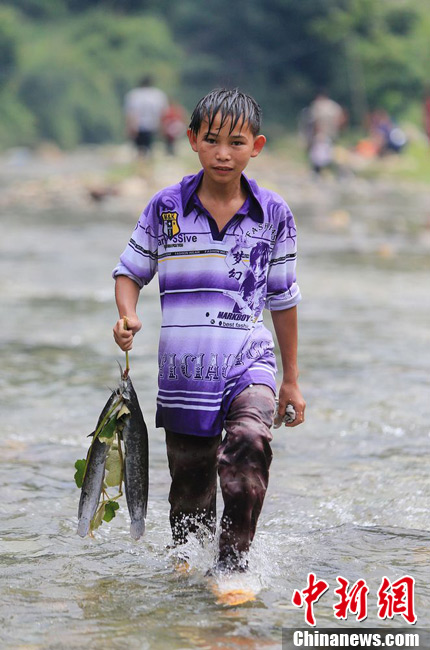 圖為7月9日，一名男孩在鬧魚節(jié)活動中抓到了兩條魚。譚凱興 攝