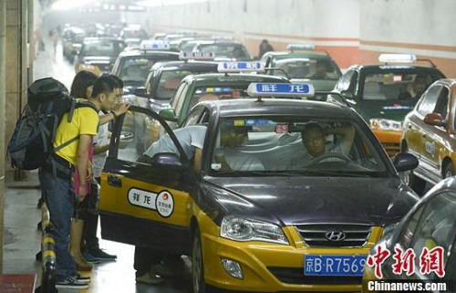 市民在北京西客站出租車候車點(diǎn)準(zhǔn)備乘車。中新社發(fā) 侯宇 攝