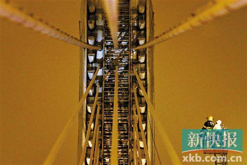 截至今日零時(shí)，男子仍未有下橋舉動(dòng)。圖為公安和消防人員乘消防云梯在高空上和男子交談。