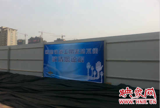道路南側圍起了白色的圍擋，墻上標示著“因地鐵施工帶來的不便敬請您諒解”的提示牌。