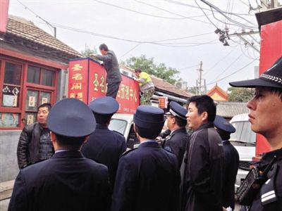 昨日下午,東城區(qū)工商、城管、公安等部門,對雍和宮附近的預(yù)測中心進(jìn)行清理整頓,站在車頂?shù)膬擅と苏鸪患摇邦A(yù)測中心”的招牌。因雍和宮、白云觀等文化景點外聚集大量算命先生,被媒體稱為“算命一條街”。本版攝影/新京報記者 李寧 攝