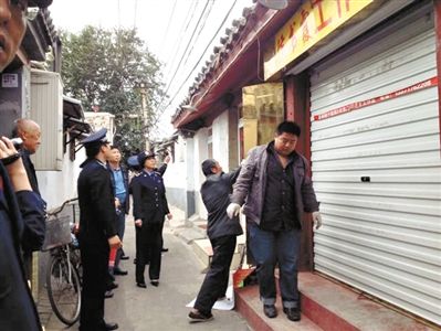 執(zhí)法人員拆除胡同里一家店面未經(jīng)審批的招牌。