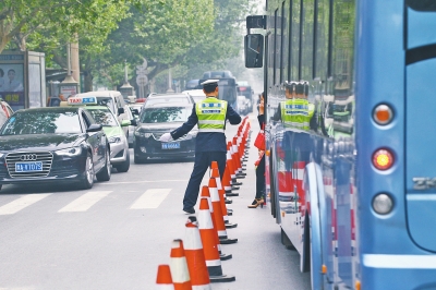 省人民醫(yī)院南門的路中間擺放反光錐，交警示意由西向東車輛從前方繞行。