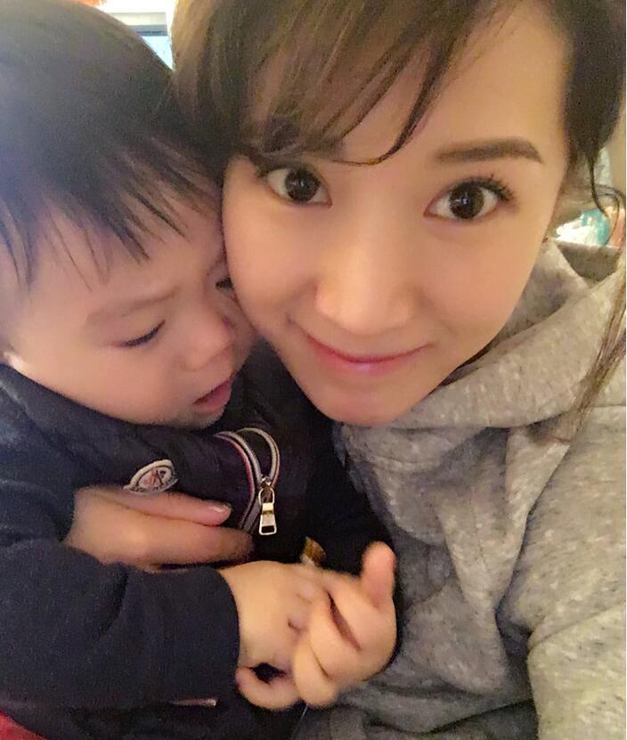 照片中李念狂吻兒子，小寶貝自顧自地玩著。