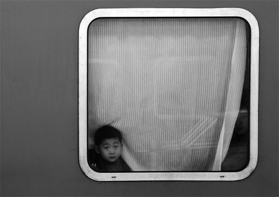 一個孩子把頭伸向窗外，他想再看送別的親人一眼