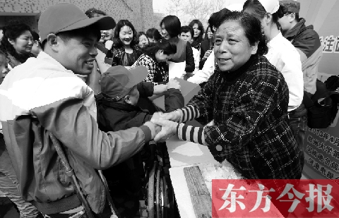 昨日，鄭大四附院的大樓前，“面人鄭”鄭玉芬（右）向前來捐款的殘疾人表示感謝