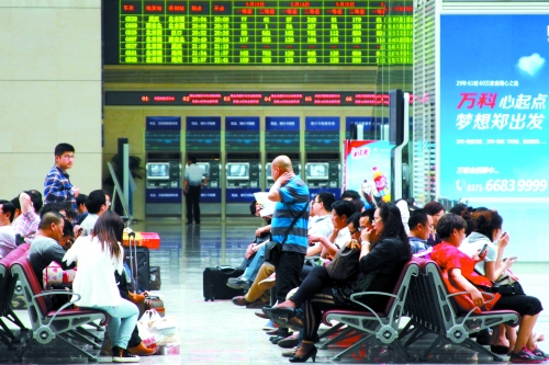 候車大廳溫度很高，一名乘客一手扇風(fēng)、一手擦汗