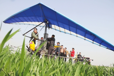 　　4月12日，在武陟縣北郭鄉(xiāng)韓余村，一架三角翼動(dòng)力滑翔機(jī)在對(duì)小麥進(jìn)行農(nóng)藥噴灑作業(yè)。為提升農(nóng)業(yè)生產(chǎn)的