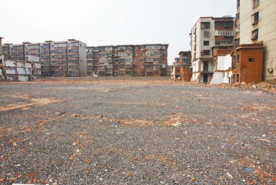 為降塵，旮旯王村拆遷后裸露的地面上鋪了一層石子。