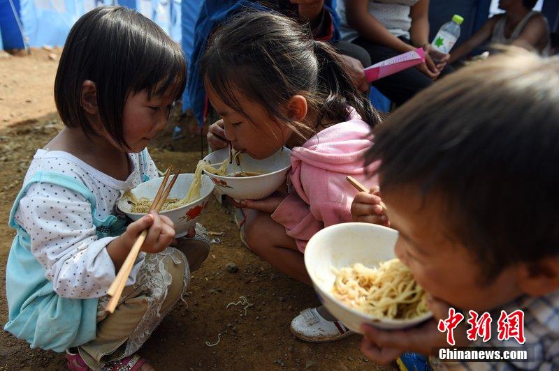 2014年8月6日，云南魯?shù)辇堫^山災(zāi)區(qū)，兒童在帳篷外吃飯。