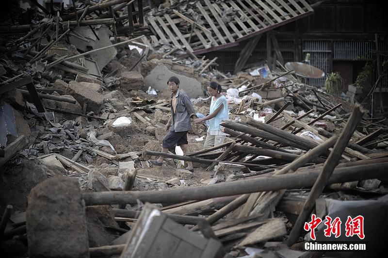 2014年8月5日，云南昭通龍頭山鎮(zhèn)老街，一對夫妻從居住房屋的廢墟中走過。