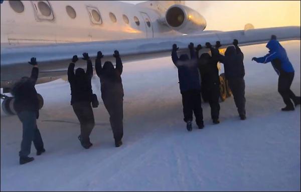 　伊加爾市一架客機起飛前被凍在了跑道上。飛機上的乘客不得不下來推飛機。
