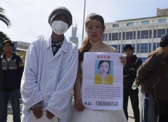 昆明火車站廣場(chǎng)上，24歲的黃習(xí)菊身穿潔白的婚紗，帶著身患白血病的弟弟征婚。