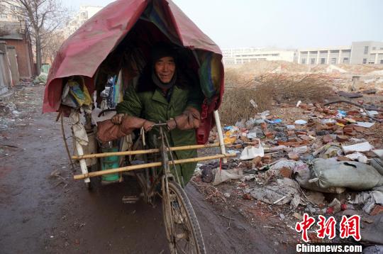 圖為老人走出窩棚，推著三輪車準(zhǔn)備出去撿拾廢品。周小云 攝